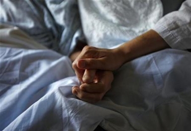 A woman holds the hand of her mother who is dying from cancer during her final hours at a palliative care hospital in Winnipeg, Canada (Reuters)
